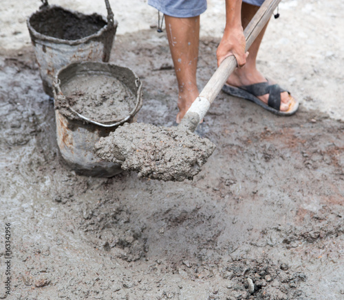 Worker stirs concrete shovel