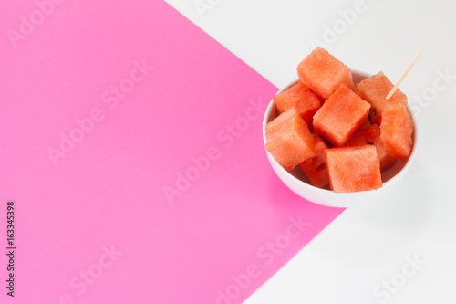 Watermelon chuncks in a white bowl, bicolored background photo