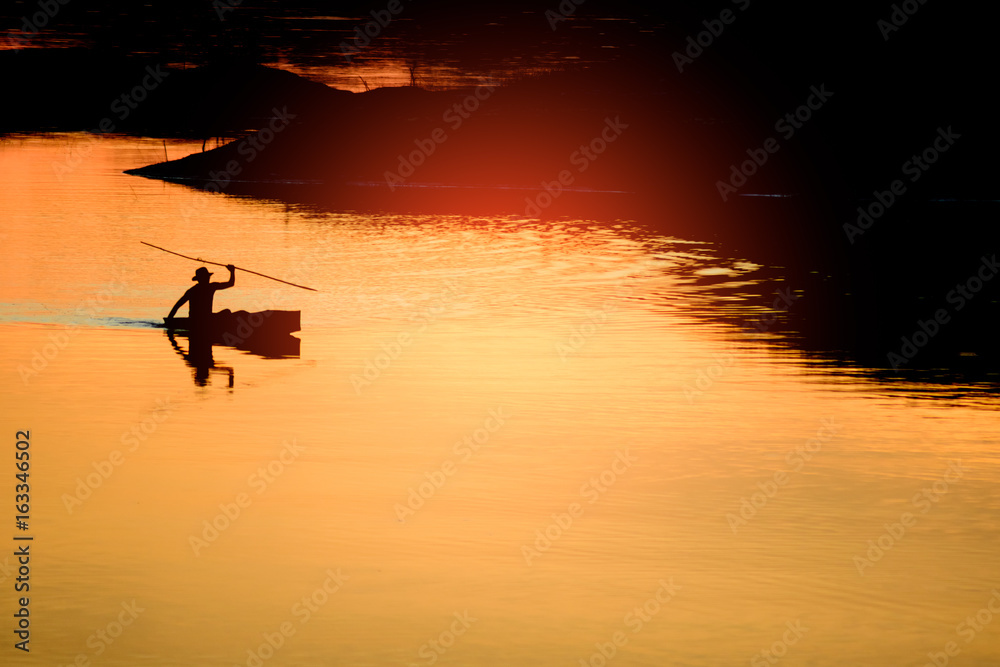 The man sailing boat in the river at sunset after fishing time,silhouette abstract background.