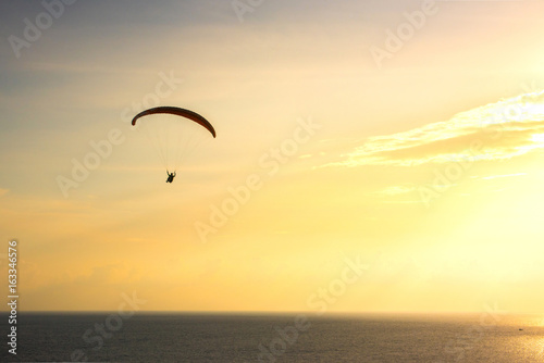 Silhouette of paraglider soaring over sea at sunset,Phuket,Thailand.