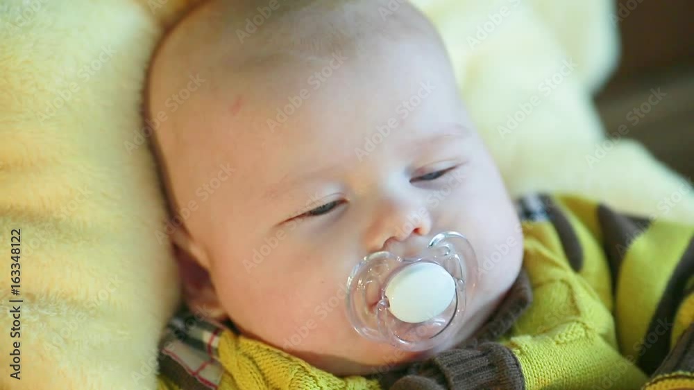 Beautiful little European-looking child lying on his back with a pacifier in his mouth Beautiful little European-looking child lying on his back with a pacifier in his mouth