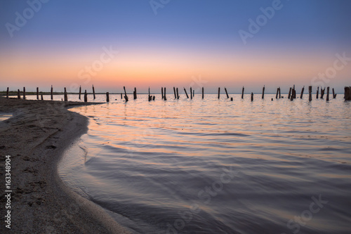 Landscape of lake at sunset / Abandoned destroyed wooden pier on lake at sunset