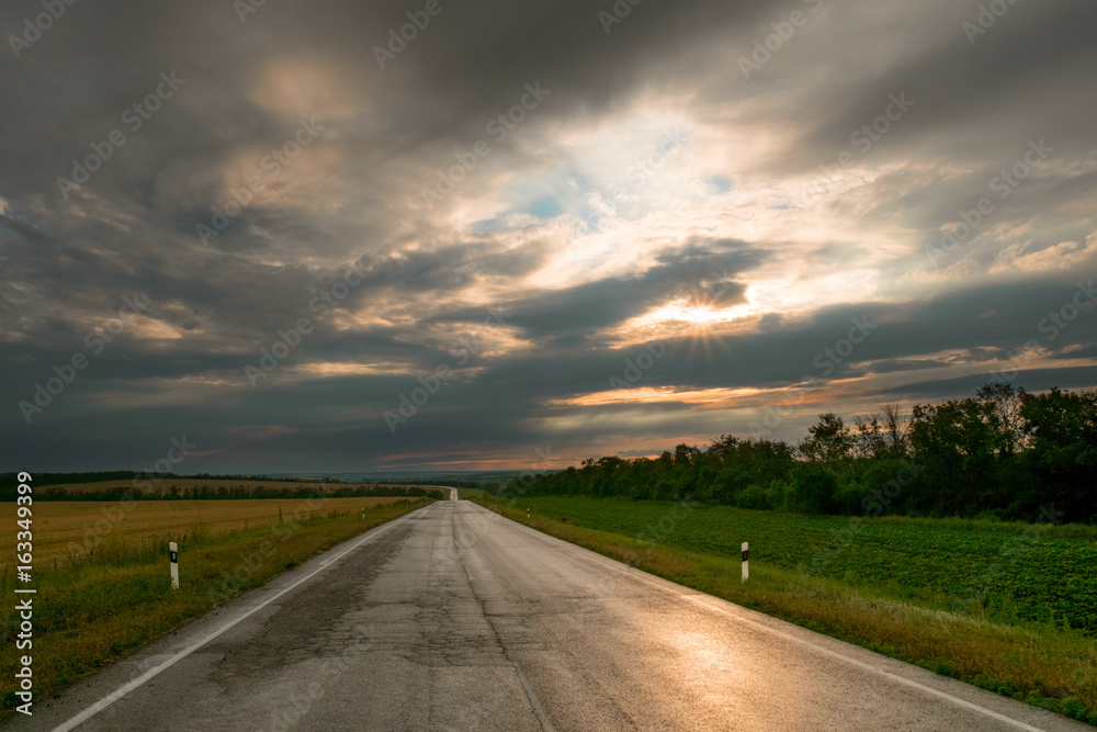the road in the evening sunset through the clouds