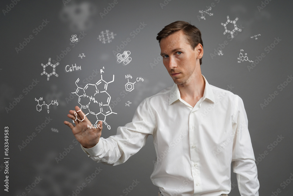 Man scientist in white shirt working with chemical formulas on gray background. Man scientist in white shirt working with chemical formulas on gray background.