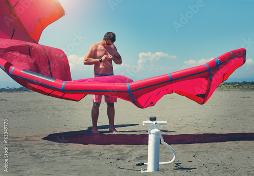 Kitesurfers on the beach prepare sport equipment for riding