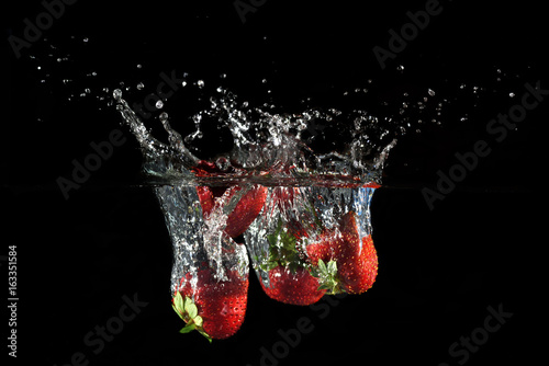 Strawberries splashing into water