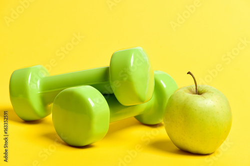 Apple and dumbbells: fresh fruit and sports equipment