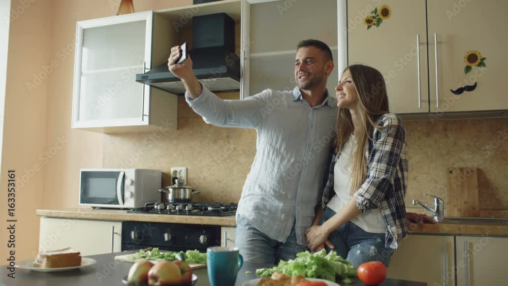 Young happy couple having online video chat in the kitchen at home Young happy couple having online video chat in the kitchen at home