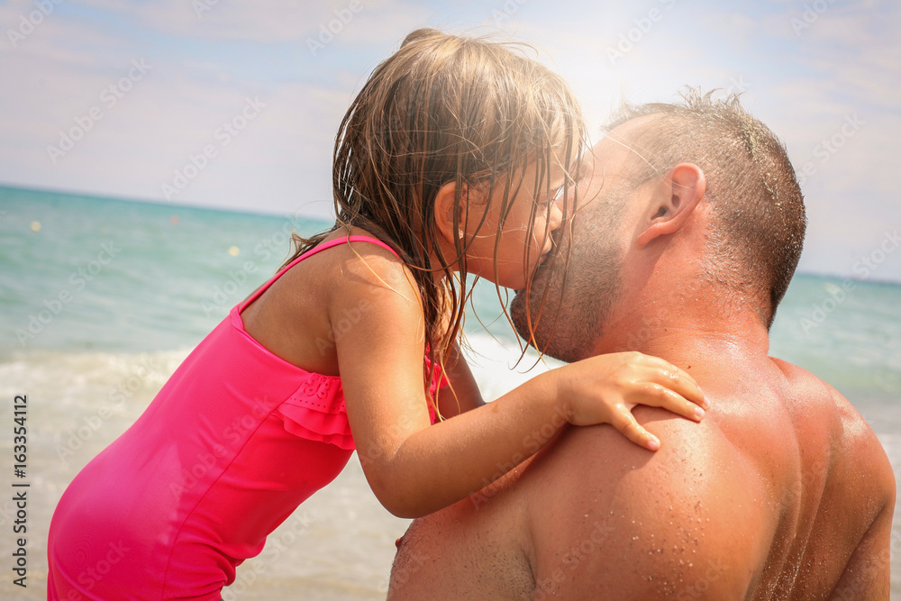 Little girl giving kiss her father. Happy father and daughter enjoying on the beach. Little girl giving kiss her father. Happy father and daughter enjoying on the beach.