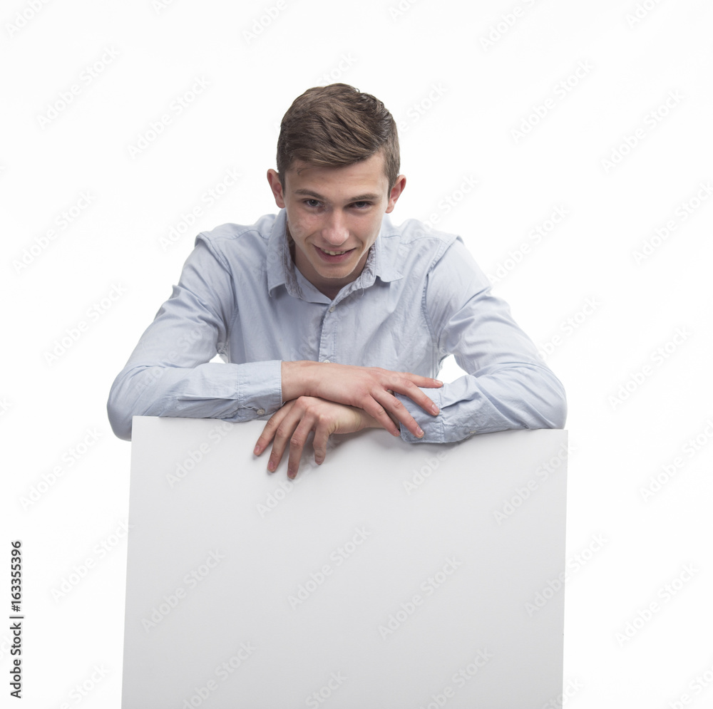 Young happy man portrait of a confident businessman showing presentation, pointing paper placard gray background. Ideal for banners, registration forms, presentation, landings, presenting concept.