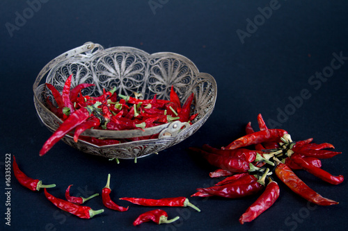 Red Chili pepper in a silver vase on a black background