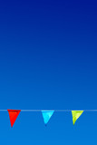 Bunting with three multicolor triangular party flags against blue sky.
