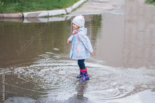 Fototapeta Naklejka Na Ścianę i Meble -  Little girl jumping in the puddle