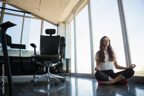 Young businesswoman doing yoga on floor