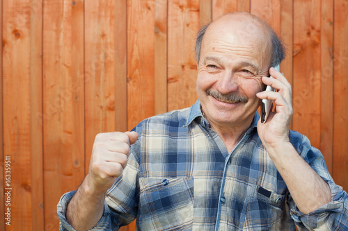 Happy caucasian man with mustache talking on mobile phone.