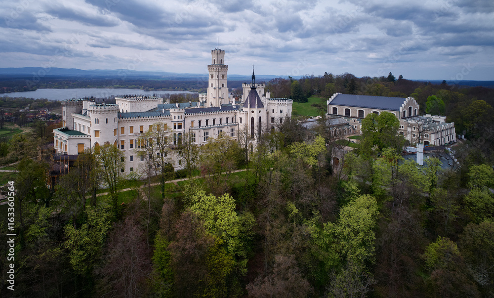 Aerial view on most beautiful, fairytale Czech castle, neo-gothic castle Huboka.Famous, like Wndsor chateau placed in a large English park. View from park side against dramatic sky. Czech landscape.