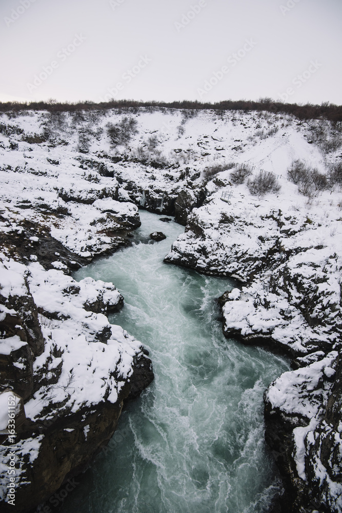Hvítá river flowing near Hraunfossar waterfall, winter season with ice and snow, long exposure Hvítá river flowing near Hraunfossar waterfall, winter season with ice and snow, long exposure