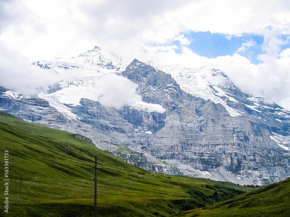 Landscape view of Swiss alps snow covered mountains and green hills