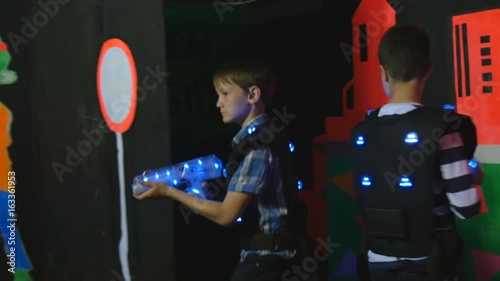 Two boys in the equipment for playing laser tag walk through the labyrinth