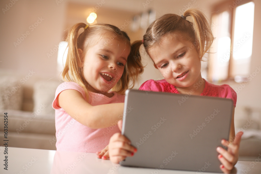 Two little sisters using tablet. Two little sisters using tablet.