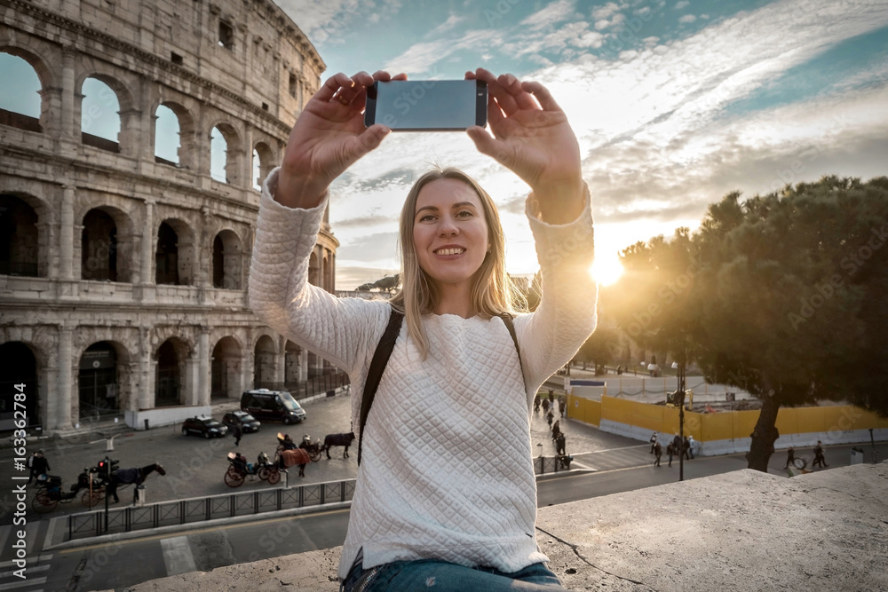 Woman tourist selfie with phone camera in hands near the Coliseu