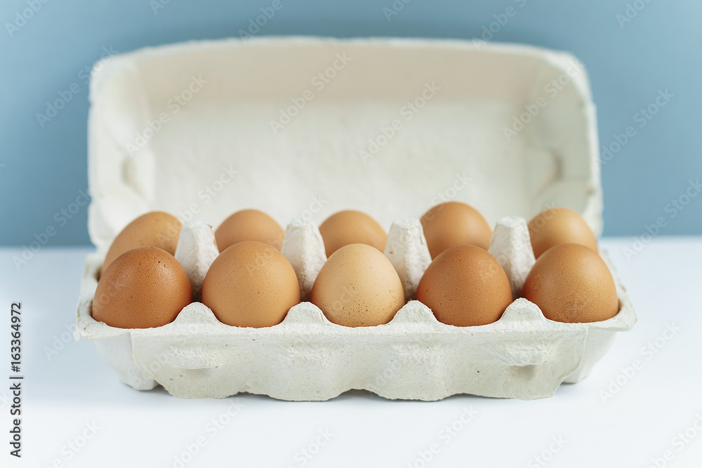 Brown eggs in open cardboard package on the background, closeup, front view