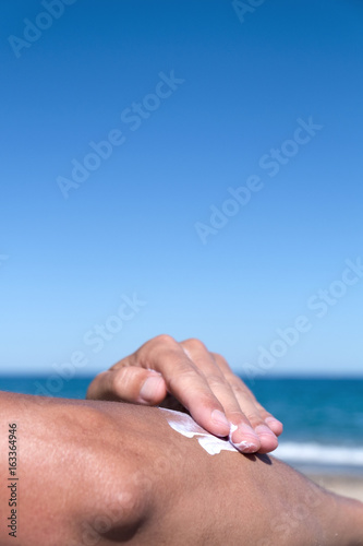 man applying sunscreen to his arm