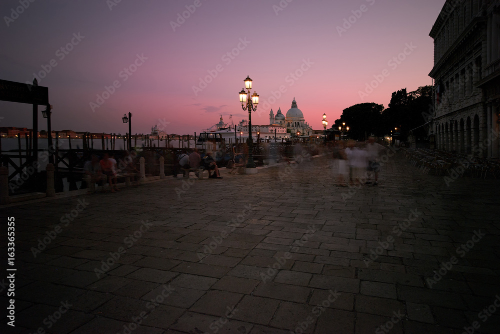 View on historic Basilica di Santa Maria della from Saint Mark square in colorful, pink dusk. Tourists blurred by long exposition, hotspot in Venice, Italy.