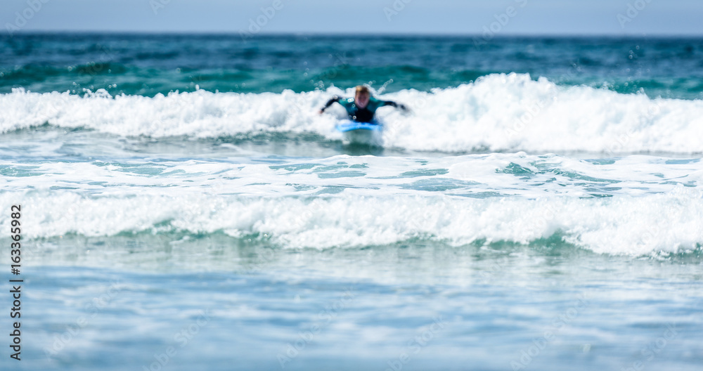 Surfer woman with surfboard is paddling on the wave. Surfer woman with surfboard is paddling on the wave.