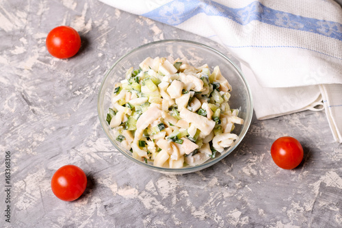 Salad with squid, egg and cucumber in a glass bowl