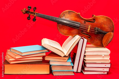 Music instrument old violin on a book and pile of books