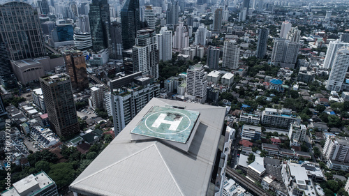 Aerial drone view of helipad isolated on top of the skycraper in Bangkok city during cloudy day photo