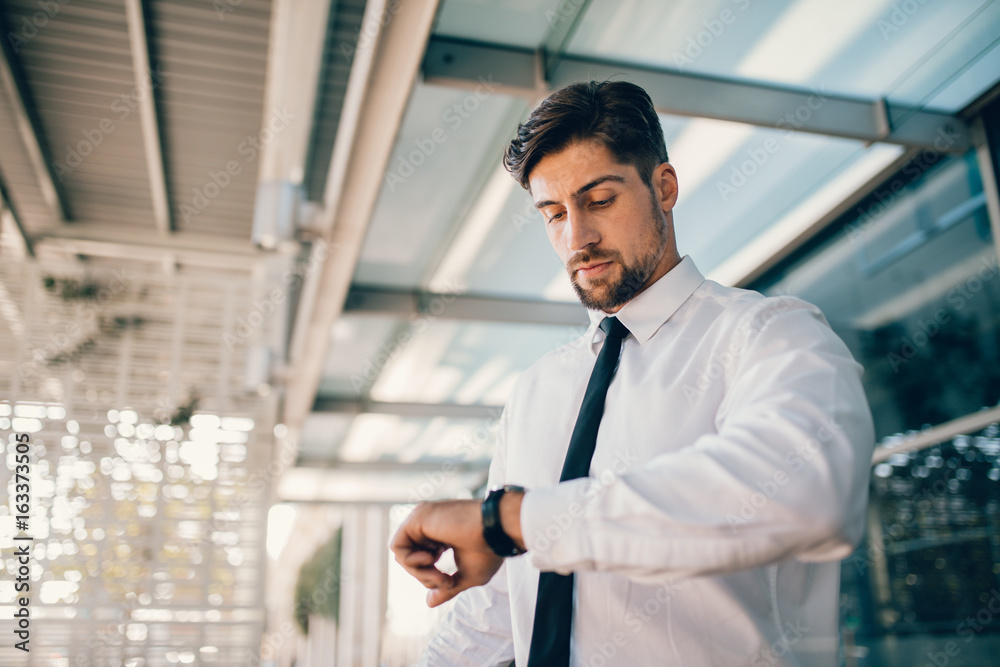Business executive checking time outside airport Business executive checking time outside airport