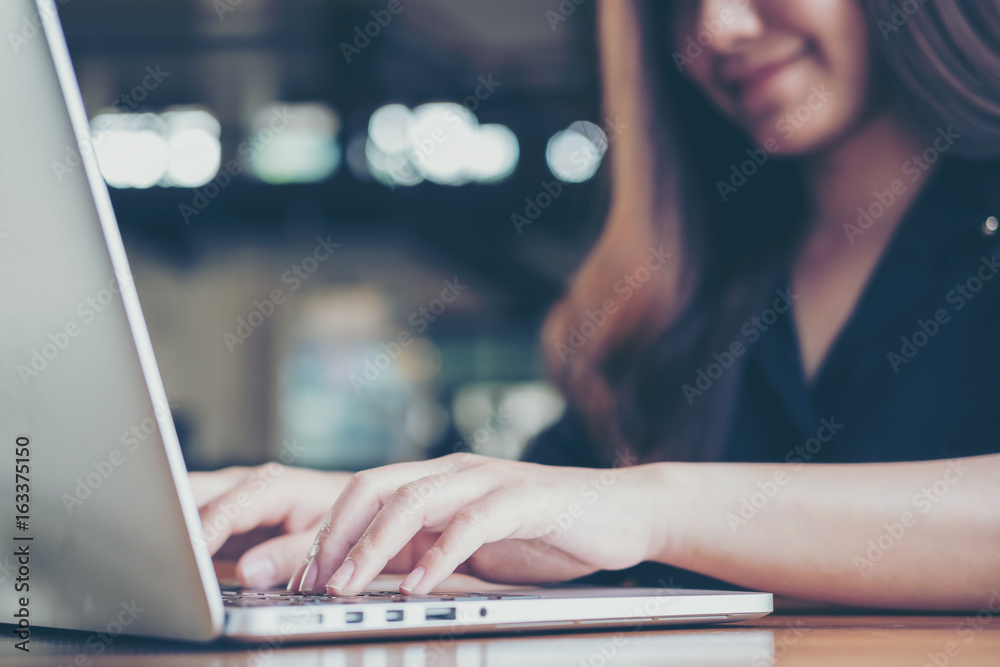 Closeup image of an Asian business woman working and typing on laptop keyboard in office Closeup image of an Asian business woman working and typing on laptop keyboard in office