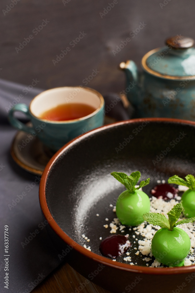 Chef's dessert from apples, chocolate, mint and caramel glazed in form of small apples with leafs. Served with teapot and cup of hot black tea. Chef's dessert from apples, chocolate, mint and caramel glazed in form of small apples with leafs. Served with teapot and cup of hot black tea.