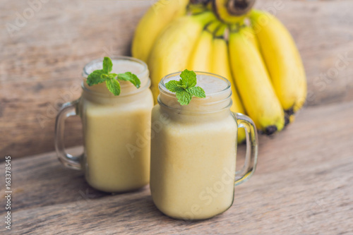 Banana smoothies and bananas on an old wooden background photo