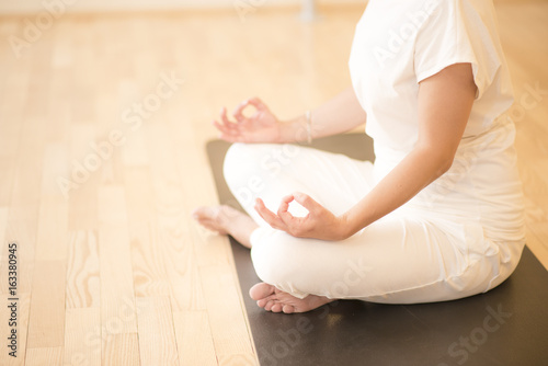 Young beautiful woman meditating in lotus pose sitting on the floor