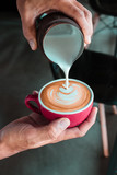 Pouring milk process from pitcher make coffee latte art by Barista in coffee shop