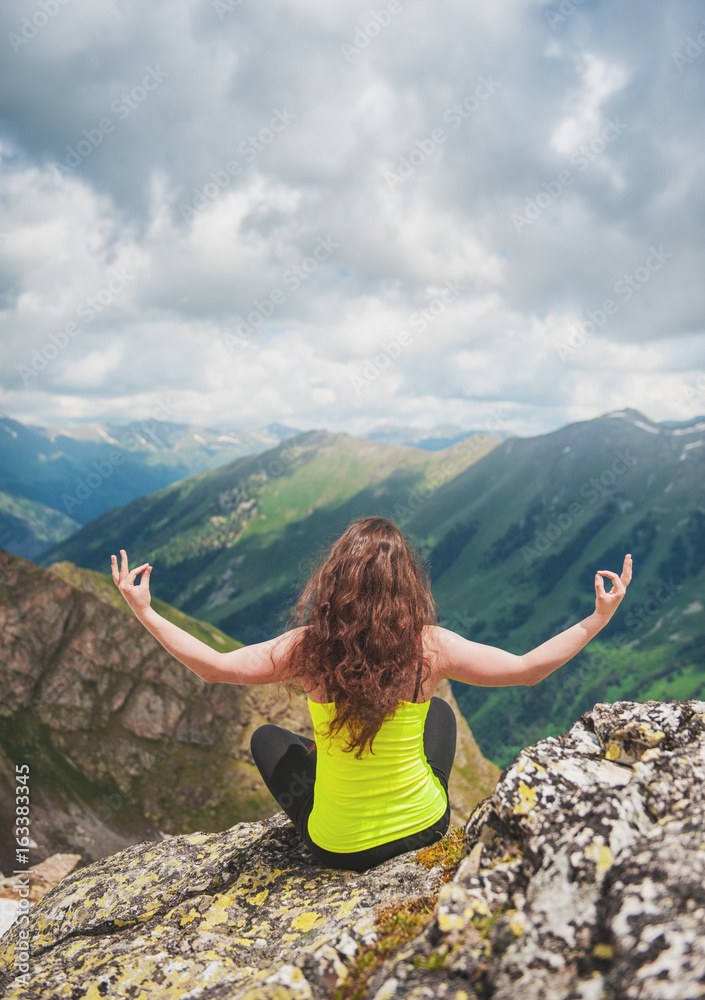 Woman doing exercise on the top of mountain