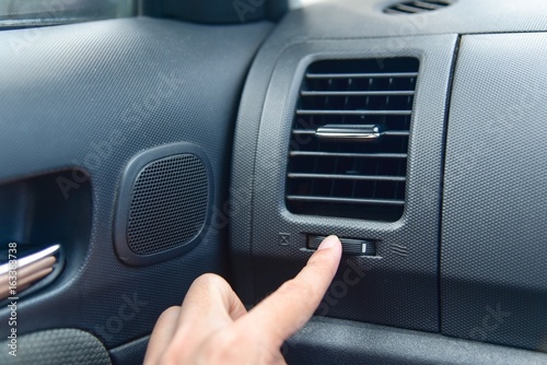 Hand Turning On Air Conditioner Vents in a Car © panithi33