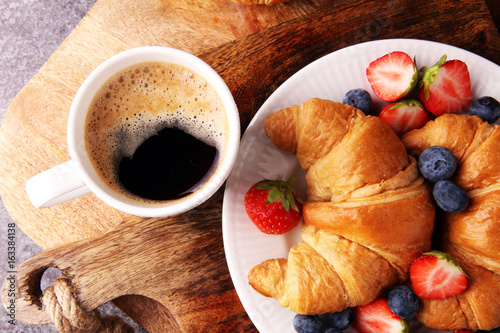 Delicious breakfast with fresh croissants and ripe berries on old marble background