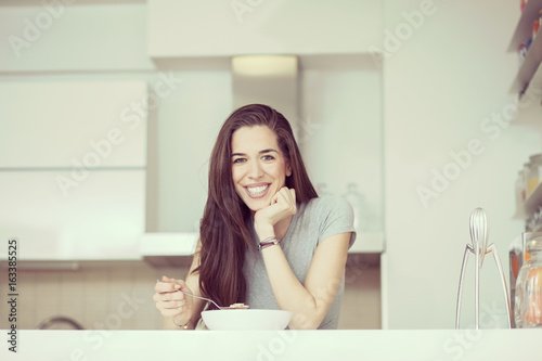 Beautiful young  woman breakfast cereals in the kitchen