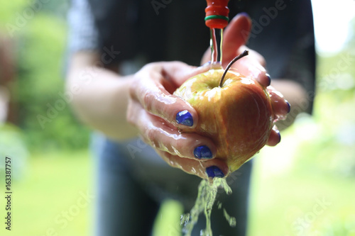 Ekologiczne owoce prosto z drzewa. Kobieta myje jabłko pod bieżącą wodą.