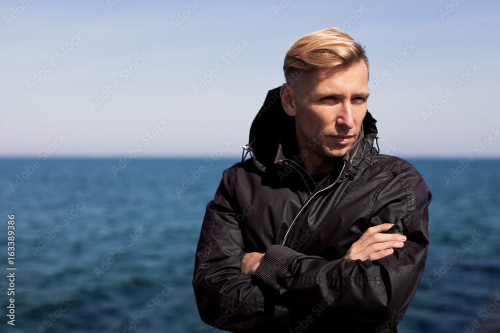 Man in windcoat posing on sea