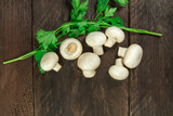 Overhead photo of white mushrooms with green parsley leaves