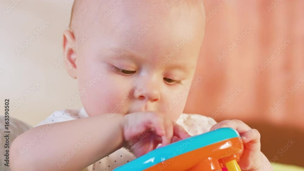 Baby sitting on the bed and playing with a toy. Close-up shot. Soft focus Baby sitting on the bed and playing with a toy. Close-up shot. Soft focus