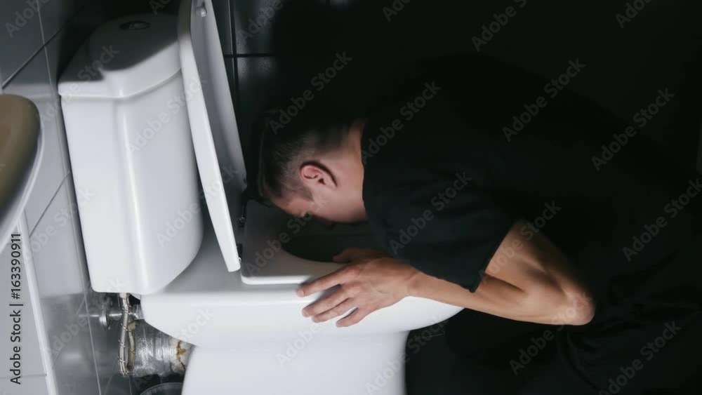 man throwing up violently into the toilet in the bathroom man throwing up violently into the toilet in the bathroom