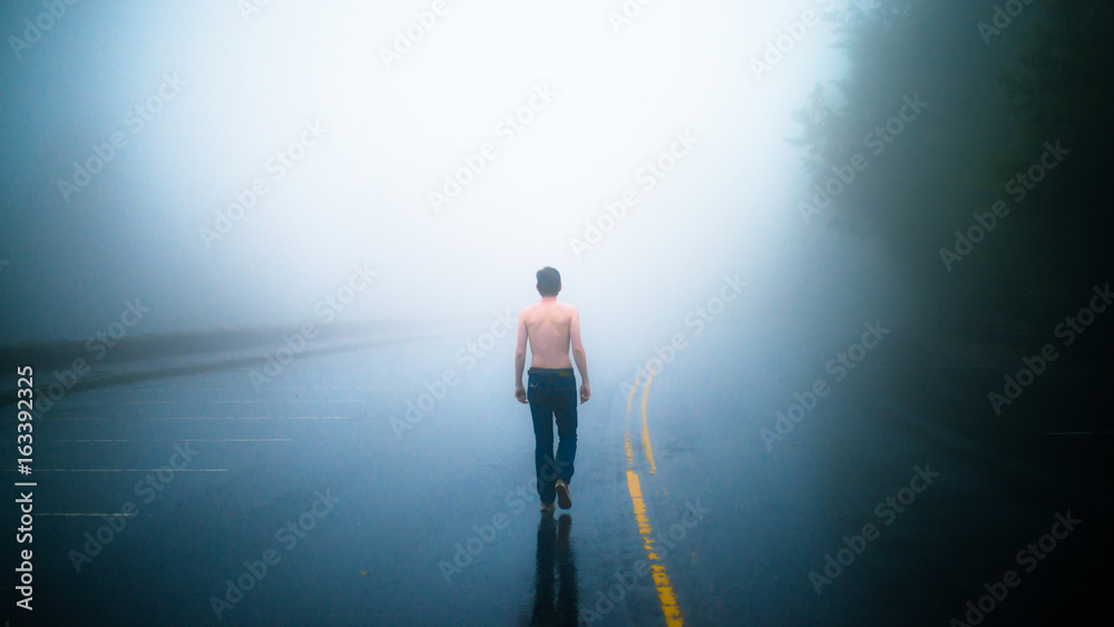 Fototapeta premium Homme torse nu qui marche sur une route brumeuse dans le Parc National Great Smoky Mountains dans le Tennessee aux Etats Unis