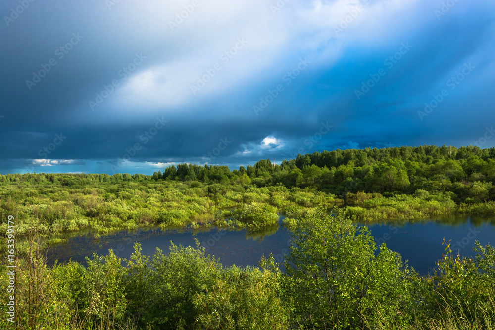 Landscape with a small lake and stormy skies.
