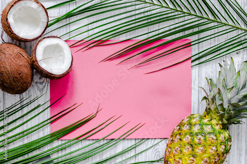 Concept of summer tropical fruits. Pineapple, cocount and palm branch on wooden table background top view mockup